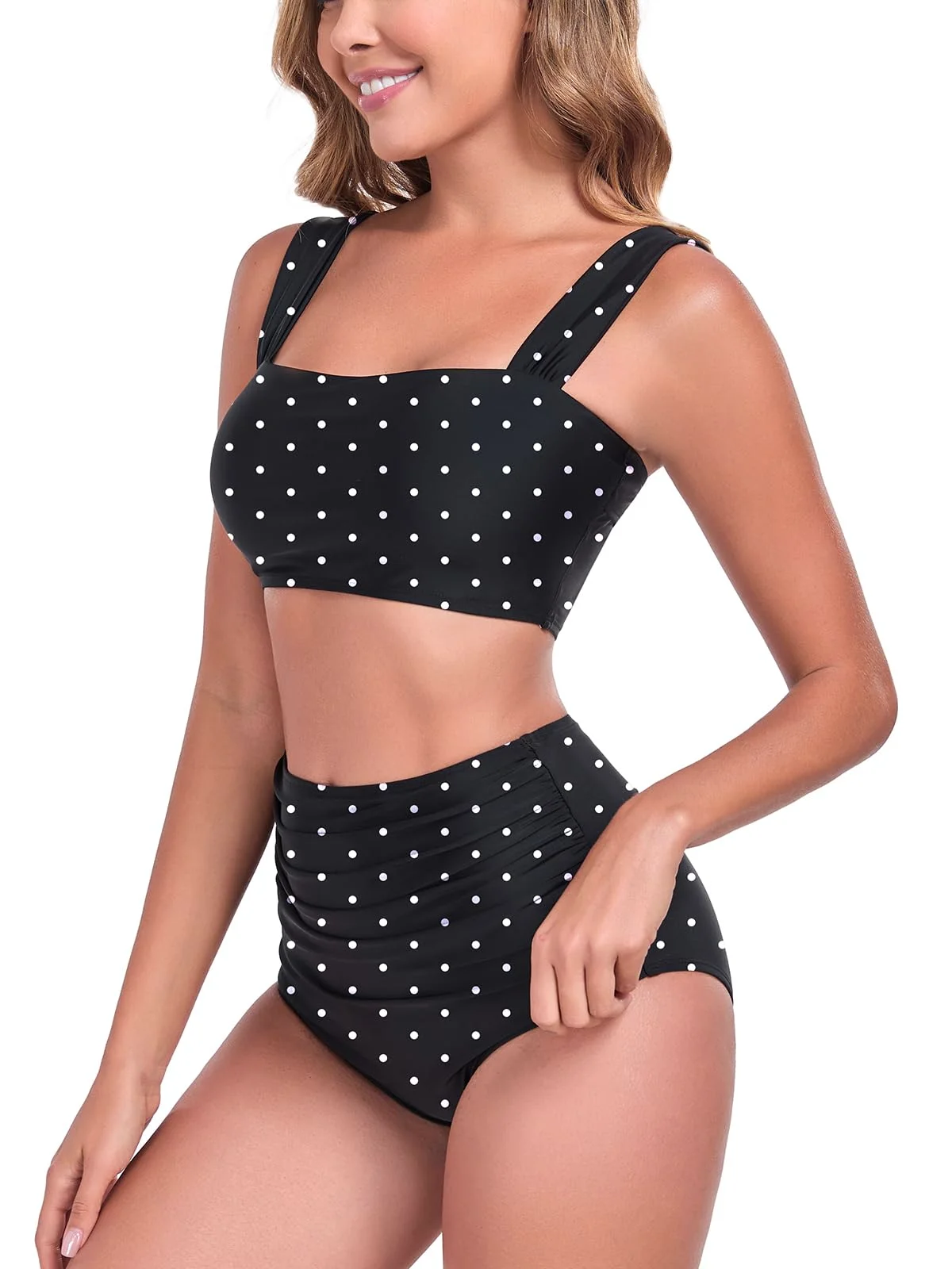 The Ocean Blues high-waisted ruched bikini set in black polka dot from the side, fingers at the waistband of the bottom